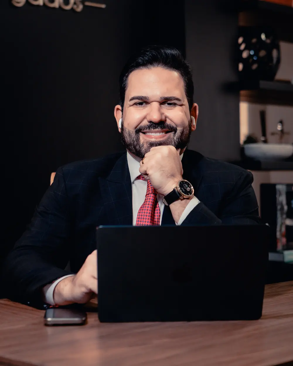 João Vítor Caldas sorrindo à mesa de trabalho, com notebook aberto
